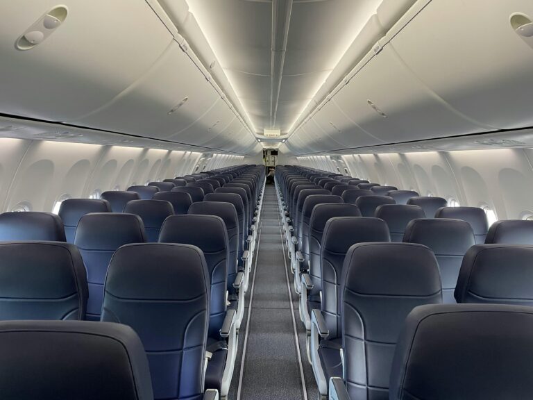 Interior of a modern airplane with empty rows and elegant seating, highlighting comfort and spacious design.
