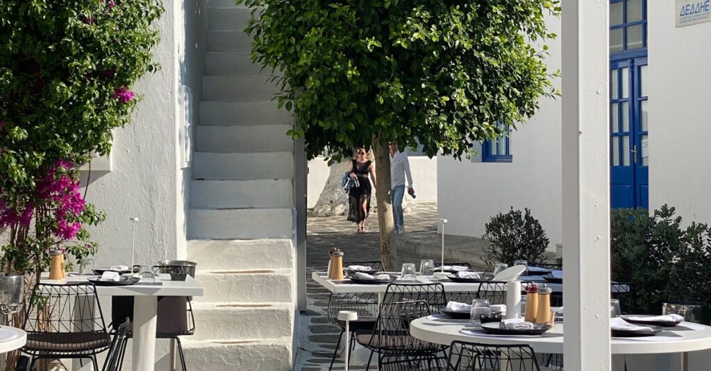 Outdoor café in Santorini, Greece with white architecture and lush greenery.